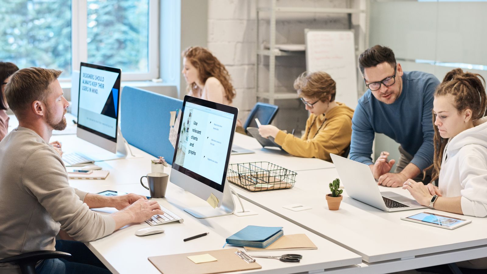 A design and development team working together at desks with monitors and laptops in a studio